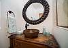 Elegant vanity with a stone bowl sink and artisan mirror.