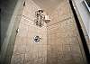 Walk-in tiled shower with glass door and built-in shelving.