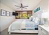 Bright king bedroom with tropical charm, TV, and garden view.