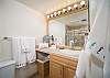 Bright bathroom with vanity lighting, walk-in shower, and fresh towels.