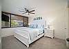 Inviting king bedroom with tropical decor, natural light, comfort.