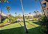 Resort view with palm trees, green lawns, and sparkling pool.