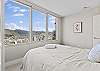 This bedroom offer space and unobstructed city and mountain views from the wall of windows.