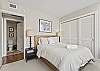 Queen size bed with two night stands and lamps compliment this spacious and comfortable second bedroom.