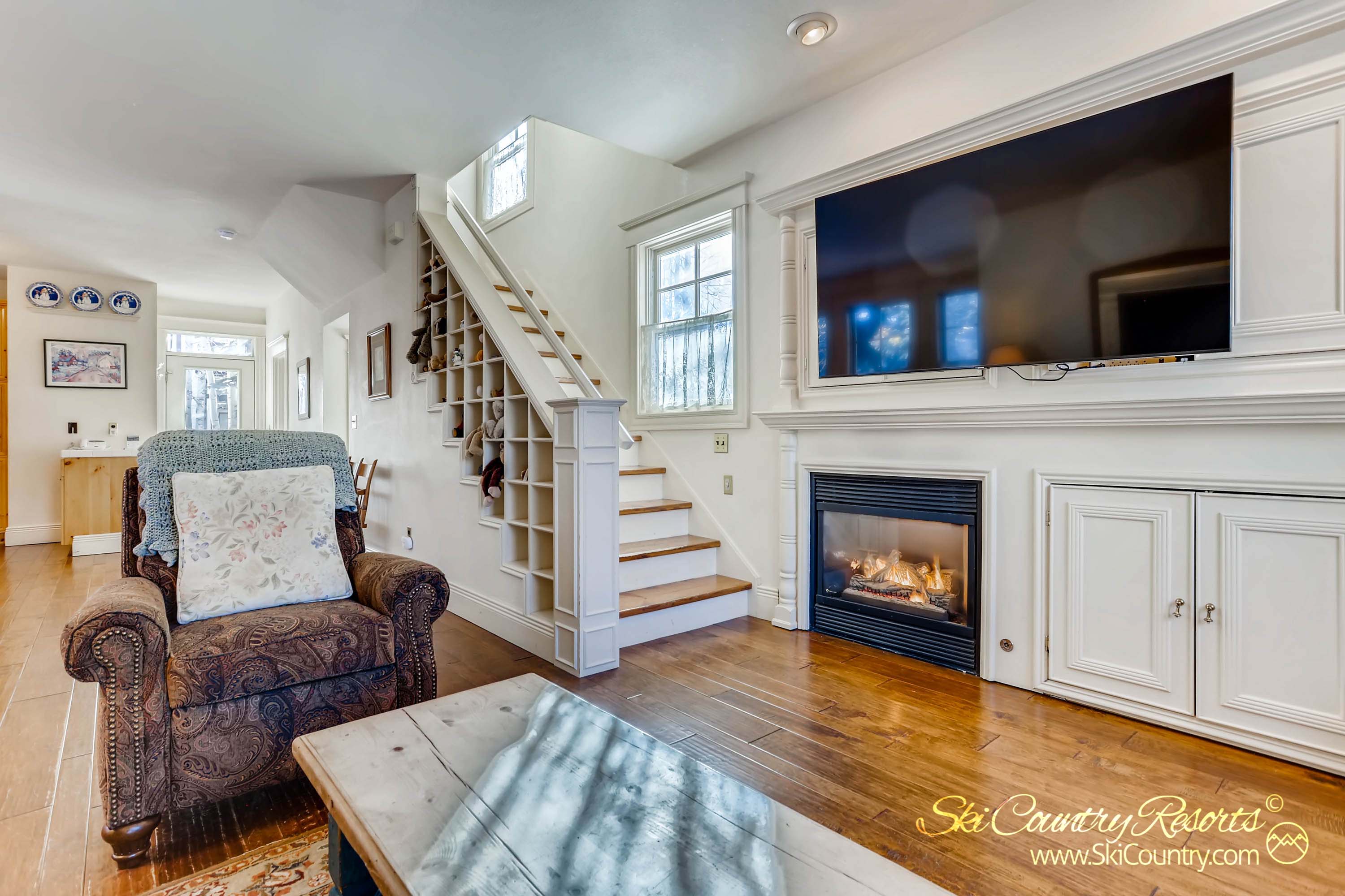 Cozy up in the main level living room with a cozy gas fireplace, elegant hardwood floors, and abundant natural light. Ample space/storage is available for your mountain gear via the built in nooks along the stairway.