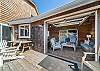 Outdoor living space with covered lounging furniture, streaming TV, dining area, open to back yard with BBQ. With uncovered sun deck for lounging