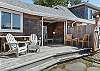 Outdoor living space with covered lounging furniture, streaming TV, dining area, open to back yard with BBQ. With uncovered sun deck for lounging