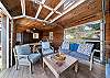 Outdoor living space with covered lounging furniture, streaming TV, dining area, open to back yard with BBQ. With uncovered sun deck for lounging