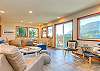 Living room with TV, wood fireplace and access to deck with mountain view. 