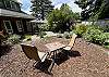 Back yard area with cocktail table, outdoor dining table with umbrella, Gas BBQ, and outdoor fire pit. 