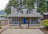 Street view with front covered porch with Adirondack chairs for relaxing in. 