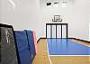 Indoor basketball court with gym mats, weight set up, and paddles for pickle ball. 