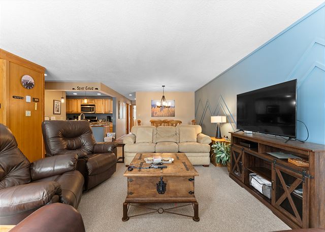 Living room with ample seating, wood-burning fireplace, TV, and queen sleeper sofa. 