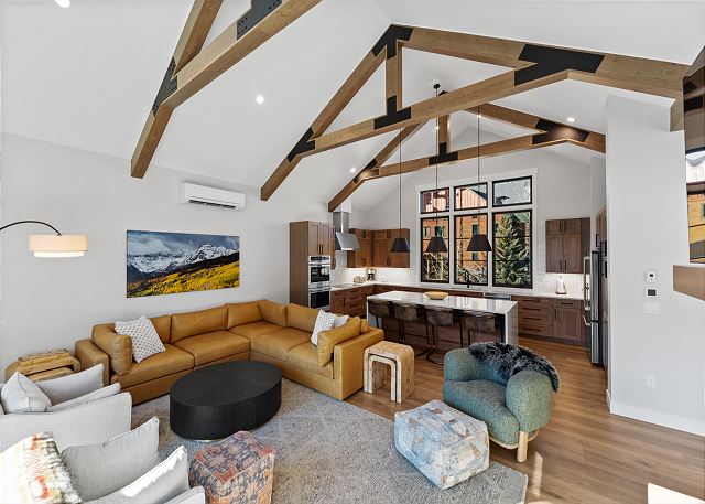 The open concept living area offers ample seating, air conditioning, cozy fireplace, a mounted TV, and a vaulted ceiling. 