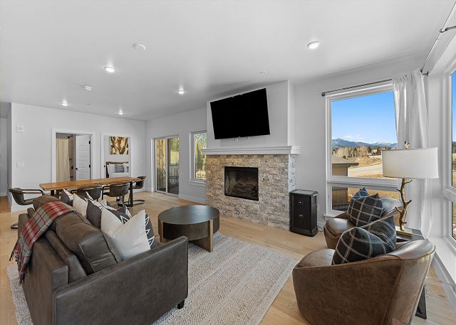 The living area offers a mounted flat-screen TV over a cozy fireplace, queen sleeper sofa, and balcony access. 