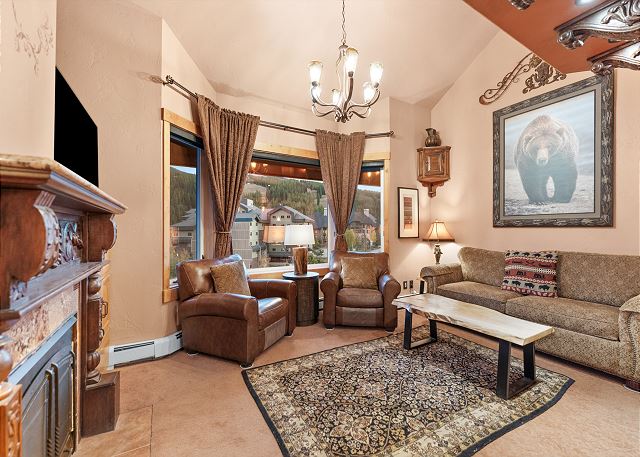 The living space offers a queen sleeper sofa, a flat-screen TV, and a cozy fireplace. 