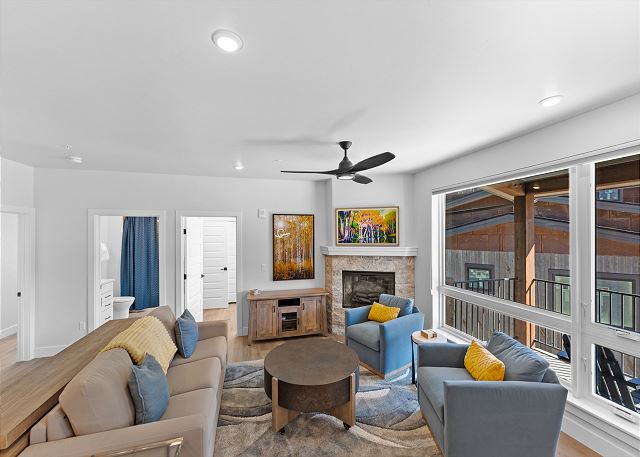 Open-concept living area with ample seating, cozy fireplace, TV, and queen sleeper sofa. 