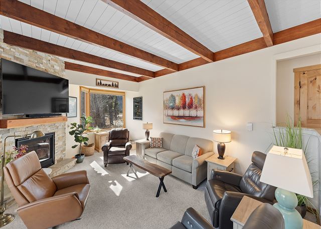 Living area with a mounted TV over a gas fireplace, ample seating, and deck access. 