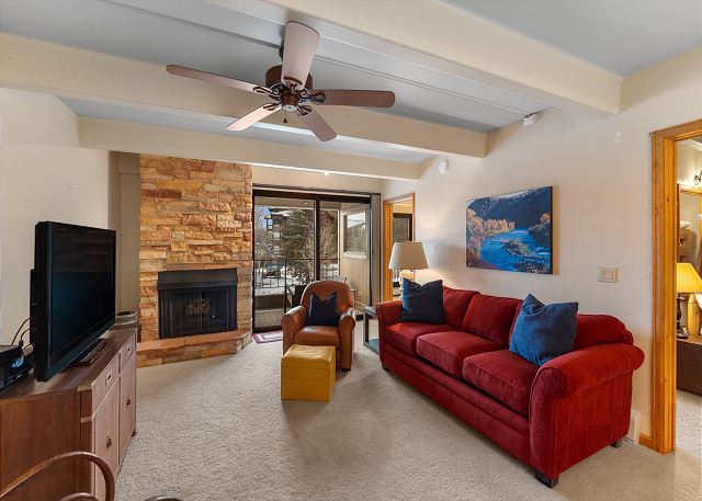Living area featuring a fireplace, TV, queen sleeper sofa, and balcony access. 