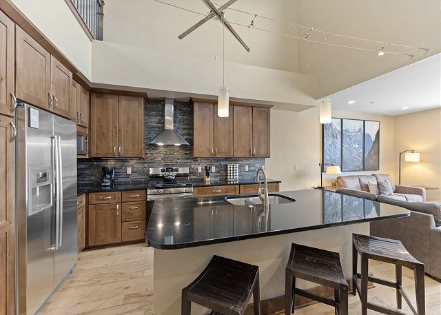 Luxury kitchen with stainless steel appliances and breakfast bar seating. 