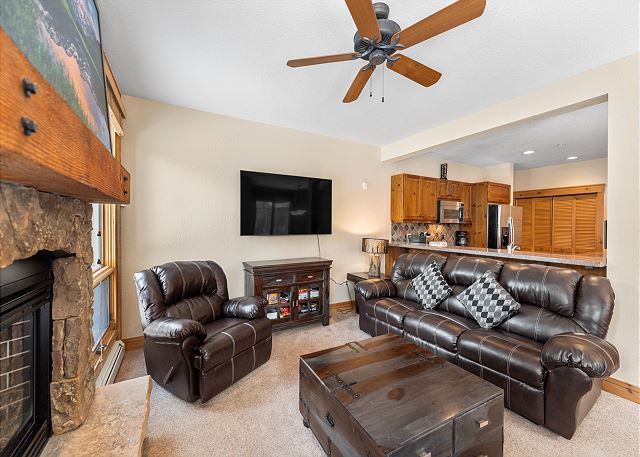 Living area with cozy seating surrounding a fireplace and mounted TV. 