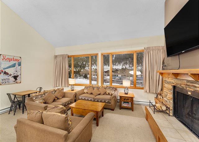 Living area featuring ample seating surrounding a cozy fireplace and mounted TV. 
