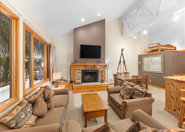 Living area featuring ample seating surrounding a cozy fireplace and mounted TV. 