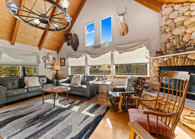 Living room with vaulted ceilings, a gas fireplace, books, and board games. 