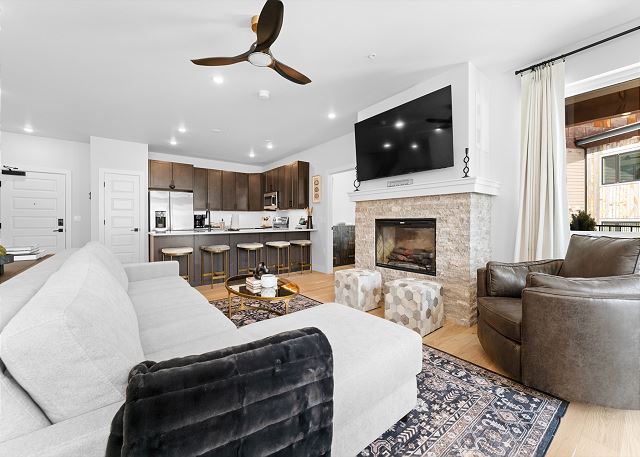 Living room with a cozy electric fireplace, mounted TV, and queen sleeper sofa. 
