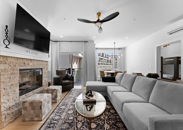 Living room with a cozy electric fireplace, mounted TV, and queen sleeper sofa. 