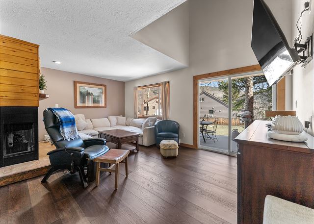 Living room with a wood-burning fireplace, mounted smart TV, massage chair, and Bluetooth speaker. 