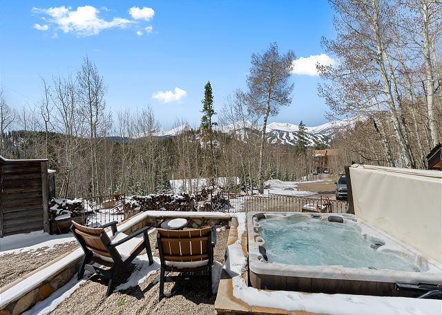 Private hot tub with outdoor seating and mountain views. 