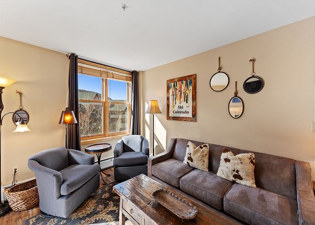 Living area with mounted flat screen TV, gas fireplace, balcony access, hardwood flooring and sleeper sofa. 