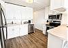 A fully equipped kitchen with crisp white cabinetry, stainless appliances, and a breakfast bar with seating