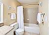 Guest bath with a tiled tub and shower combo perfect for rinsing off after the beach.