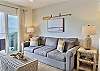 The sun-filled living room features large sliding doors that open to a private balcony with seating and a natural gas BBQ.
