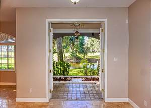 Looking out to the back patio from the kitchen with its many shade trees and often seen Florida Sea Birds. Beyond the pond is a section of the Community Golf Course.