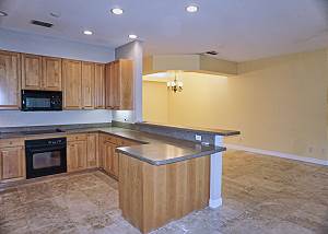 This view is from the french doors to the patio off of the kitchen and living room. This Great Room offers high ceilings, a Bar Counter that faces the Kitchen from the Living Room and space for a Formal Dining Table.