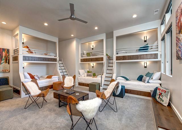 The fifth bedroom is located on the entry level and is a wonderful flex space. It is a sizable room with three, twin over full-size, custom built-in bunk beds. It offers an entertaining/gaming space with table and chairs, a 65" Smart TV with Sonos, and Xb