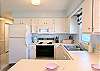 Interior view of the updated kitchen at D4 Briar Court with a white refrigerator, stove, and microwave.