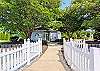 Charming park-like setting at Bethany Meadows featuring a white picket fence, picnic tables, and paved walking paths.
