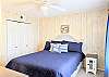 Spacious master bedroom at D4 Briar Court featuring navy coastal bedding, a white headboard, and soft yellow paneled walls.