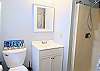 Clean, updated master bathroom at D4 Briar Court featuring a white vanity, modern lighting, and a walk-in shower.