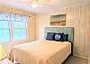 Bright guest room in D4 Briar Court with a teal headboard, coastal wall art, and ample natural light.