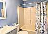 Modern secondary bathroom at D4 Briar Court featuring a grey vanity, white countertop, and nautical-themed shower curtain.
