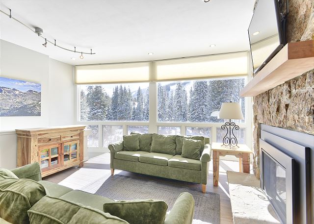 Large picture windows, natural lighting, fireplace, and access to the private balcony.