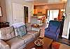 The cozy living room area has a comfortable sofa, arm chair, fireplace, and a TV. The main floor has a large, open layout. 