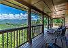 Covered deck with lounge seating and chairs overlooking the mountain view. 