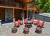 Lower patio fire pit with red chairs and barrel planters below the upper deck.