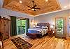 Primary bedroom on the main level with dual deck access doors and tray ceiling. 